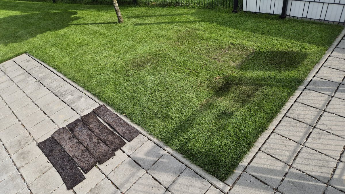 When I was burying a manhole cover years ago I thought it was a good idea to put some heavy cloth under to help hold the water. It was a mistake, the grass above felt too soft. I took it out, in couple of weeks nobody will know.