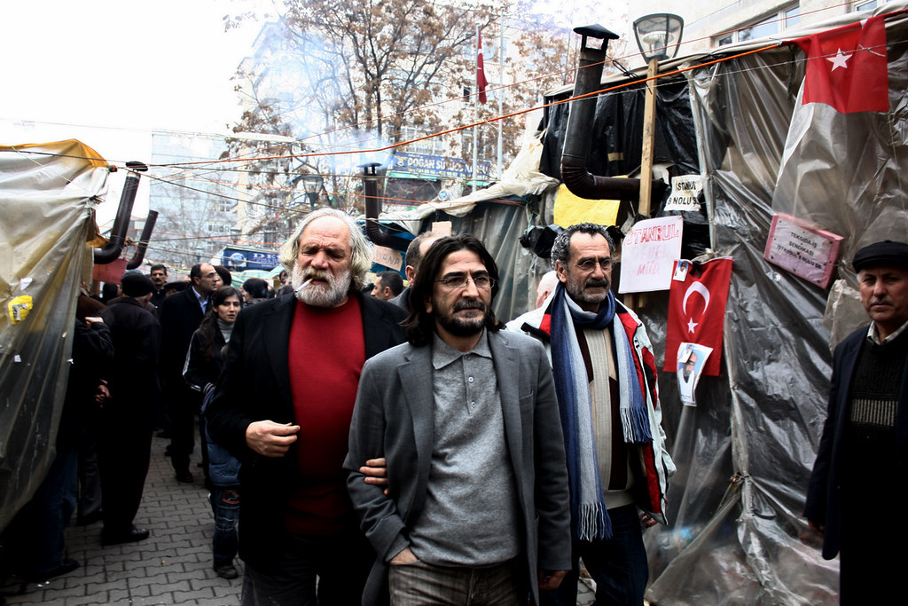 burakhanbsrn's tweet image. nihat genç'in en güzel fotoğrafı.

tekel direnişi, 2010. sağında eşber yağmurdereli, solunda menderes samancılar.

arkasında işçi çadırları, çadırdan tüten duman, emekçiye rotayı gösteren türk bayrakları.

ensesinde ankara'nın şubat ayazı...

karşısındaysa nefret ettiği sermaye.