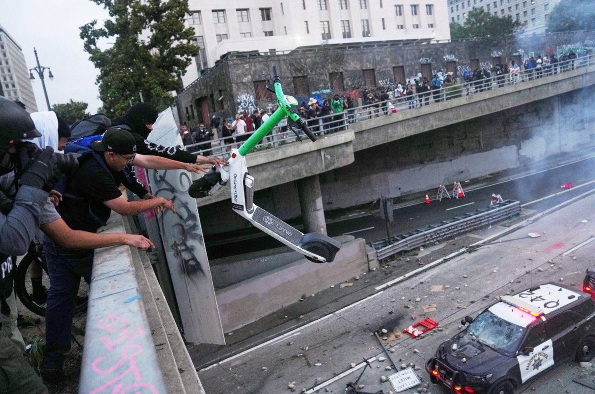 Don’t believe the lies of the Trump administration. This photo shows the peace and love it is going on in Los Angeles.  This is the culture of helping with another that Gavin Newsom has built. Look how they are catching the scooter and keeping it from falling on that police car.