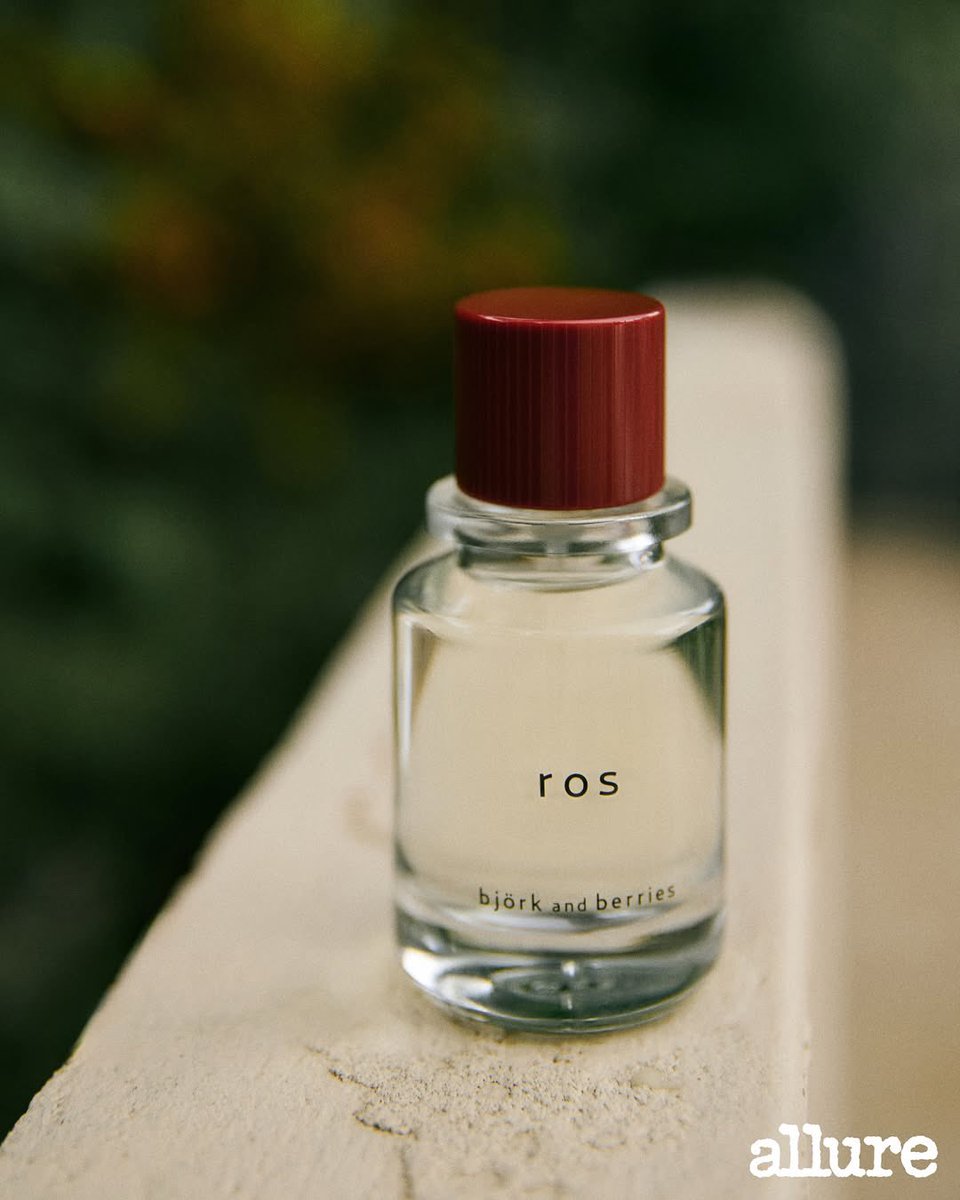 Under the softness of overgrown green, I return to the pages of ALLURE x Björk &amp; Berries. With a sleeveless black, the scent of the Ros clings to the air around me: blends with the hush of leaves and the weight of still air, turning the photo into something more than just visual.