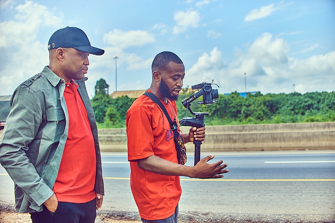 In this frame, I stand beside Ayo Ashimolowo - <a href="/wizkilaz/">WIZKILAZFILMZ</a>  the documentarist with eyes that see beyond the surface.
Together, we chase echoes of times through the lens, weaving light and sound into stories.
Stories that speak of power and people, of culture and change.
With each