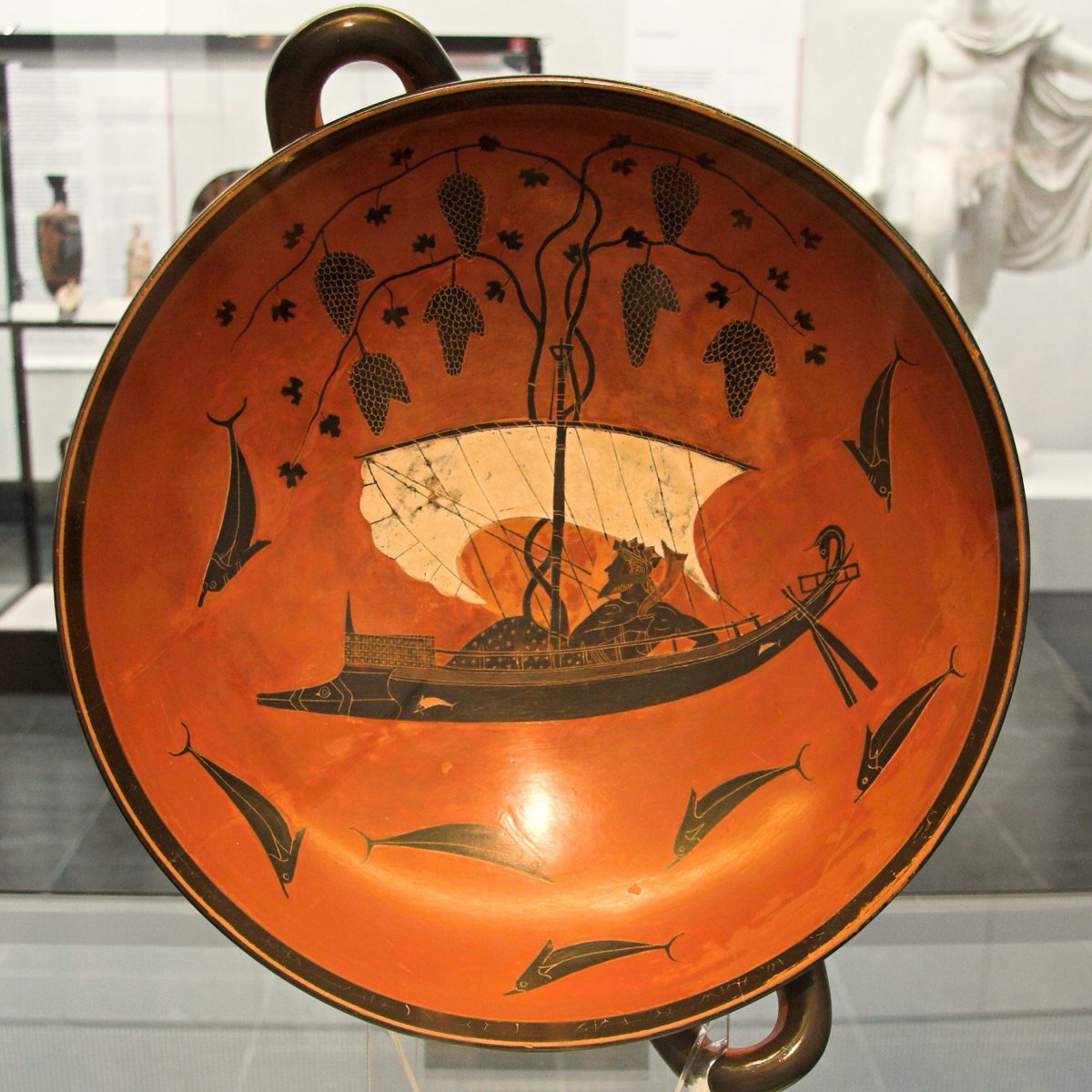 Dionysos sails the wine-dark sea, enthroned upon a ship, crowned in vine, attended by dolphins born of metamorphosis: pirates once, who tried to seize a God, now eternal symbols of divine retribution.

A vision drawn from Homeric Hymn 7, rendered in black-figure by Exekias (530