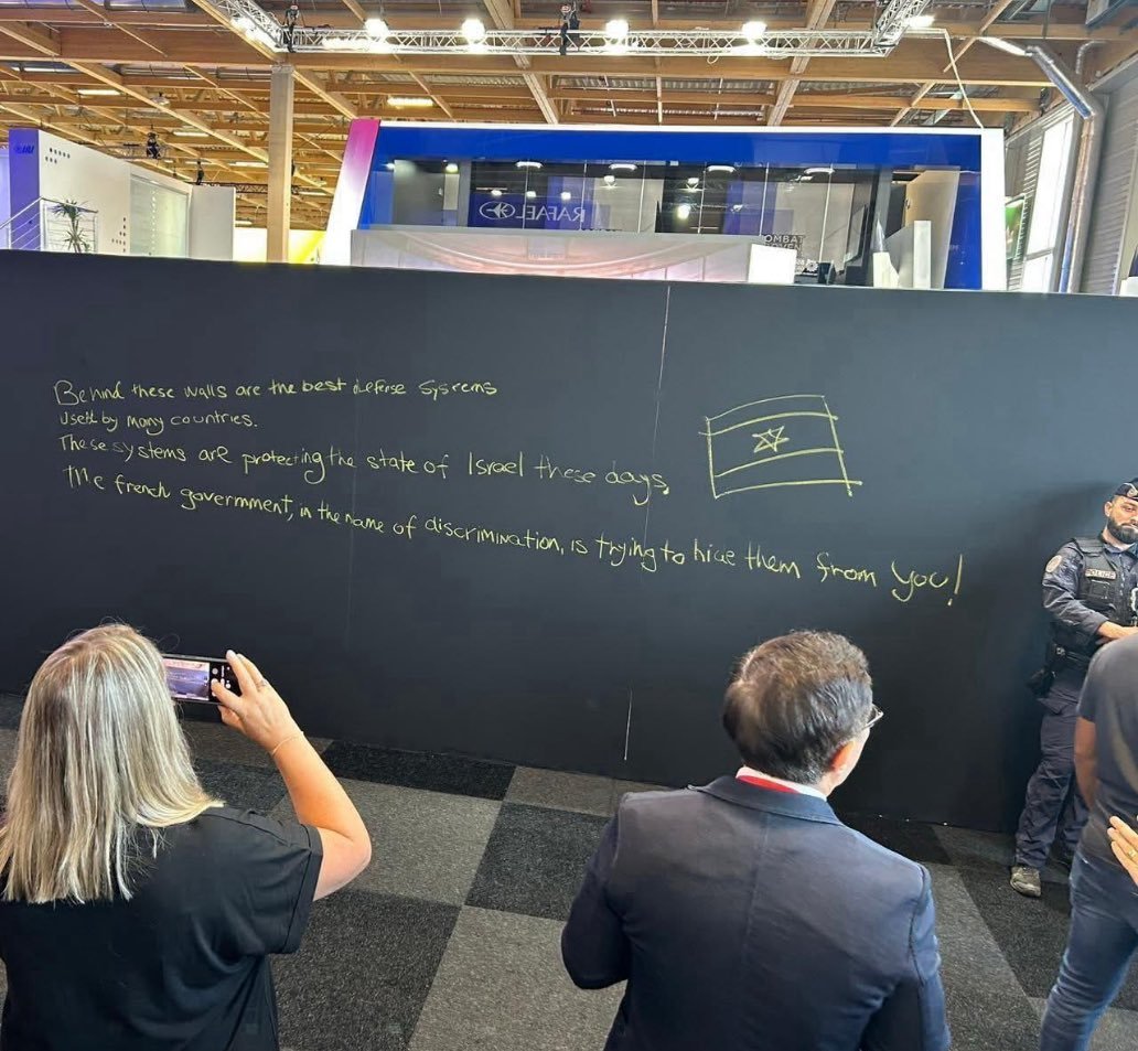 🇫🇷En este momento es el Salón Aeronáutico de Le Bourget: Francia exigió la retirada de las armas ofensivas israelíes y luego mandó levantar un muro negro alrededor de los pabellones israelíes.  Los israelíes respondieron escribiendo en el muro.