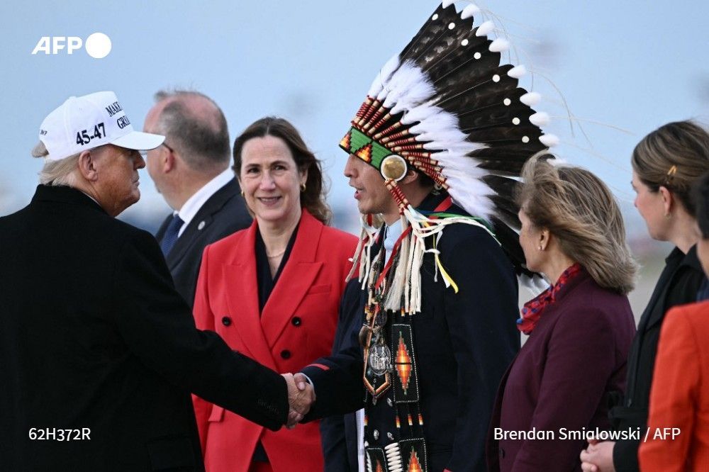 US President Donald Trump (L) is greeted by Steven Crowchild of the Tsuut'ina First Nation (3R) on his arrival at Calgary International Airport on June 15, 2025, ahead of the G7 summit