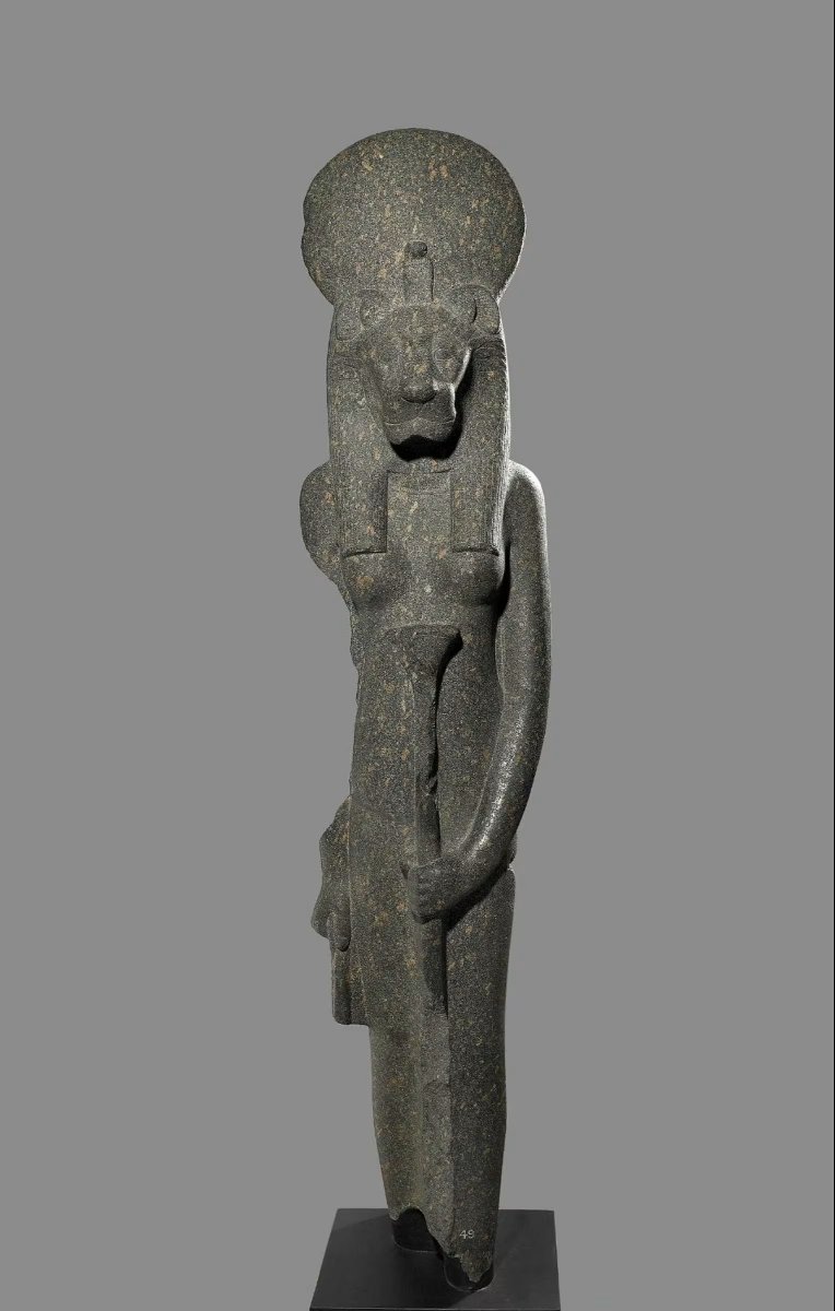 Granite statue of the warrior goddess Sekhmet, wearing sun-disc and holding a lotus-sceptre, lower section and part of right arm damaged.

New Kingdom, 18th Dynasty, ca. 1550-1292 BC.
From Thebes. Now in the British Museum. EA49