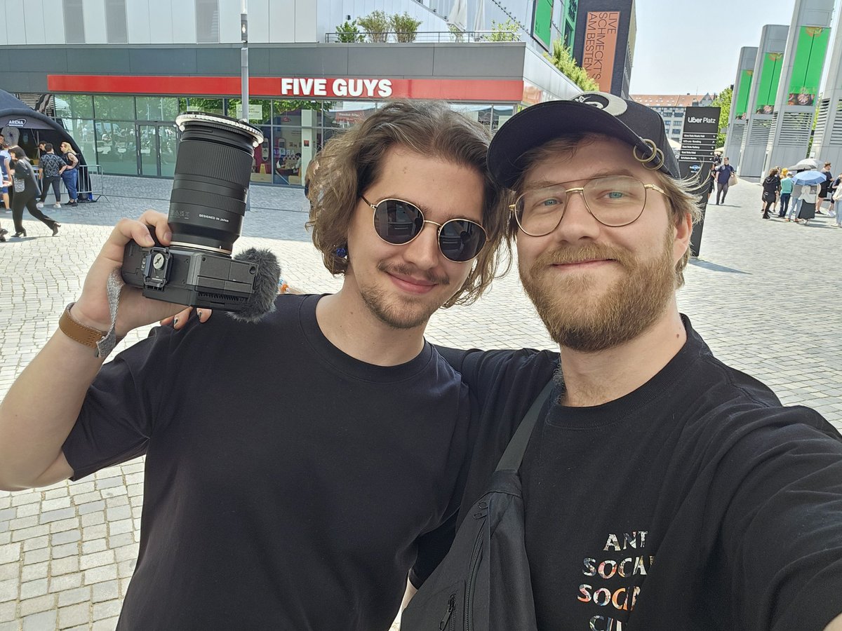 Flugmorph's tweet photo. look who I found at the Ado merch line just now! 
its @Manmode_. he doesn't like that I look (and am) taller than him XD

he also told me to mention five guys in his mouth, i think thats a reference to the restaurant in the back 🤷
sent tweet https://t.co/wGLDaZuaq5