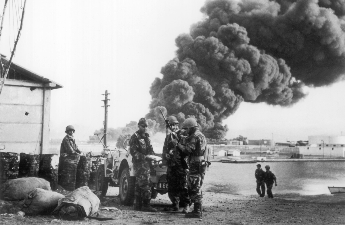 Paratroopers of the 2e RPC inspect a captured SKS carbine while an oil depot burns in the background.
Suez Crisis, 1956