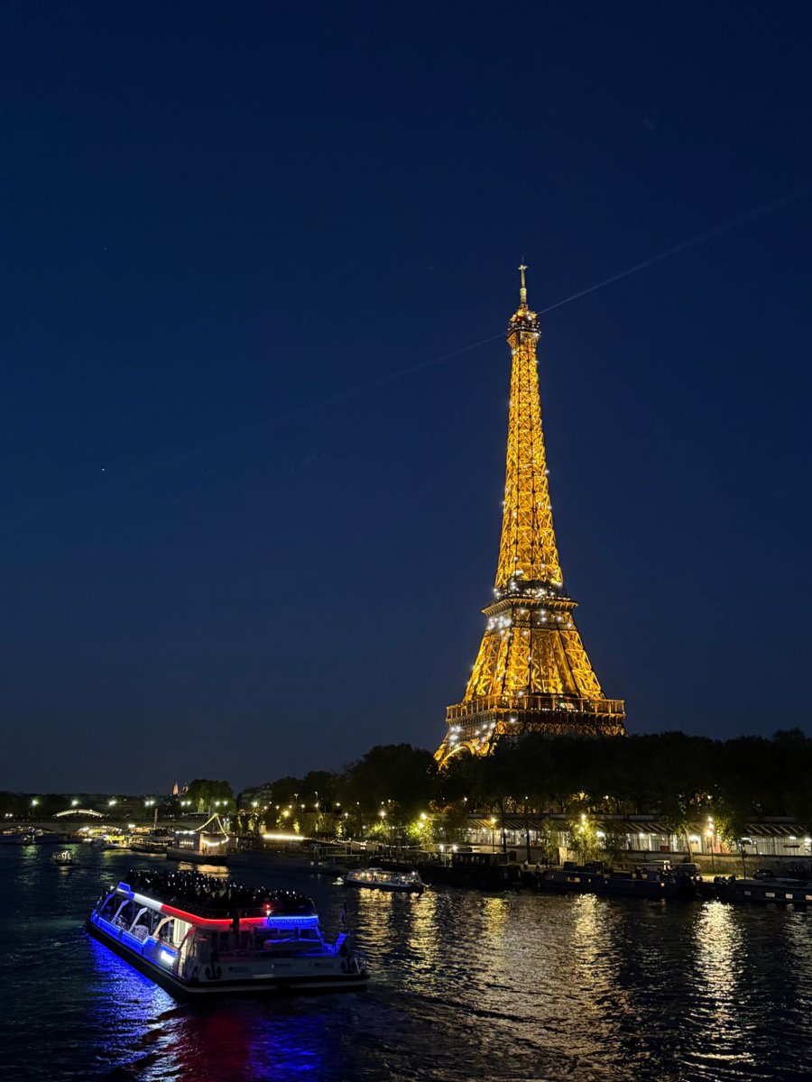 Beautiful night view of the Eiffel Tower with a illuminated boat on the Seine River.