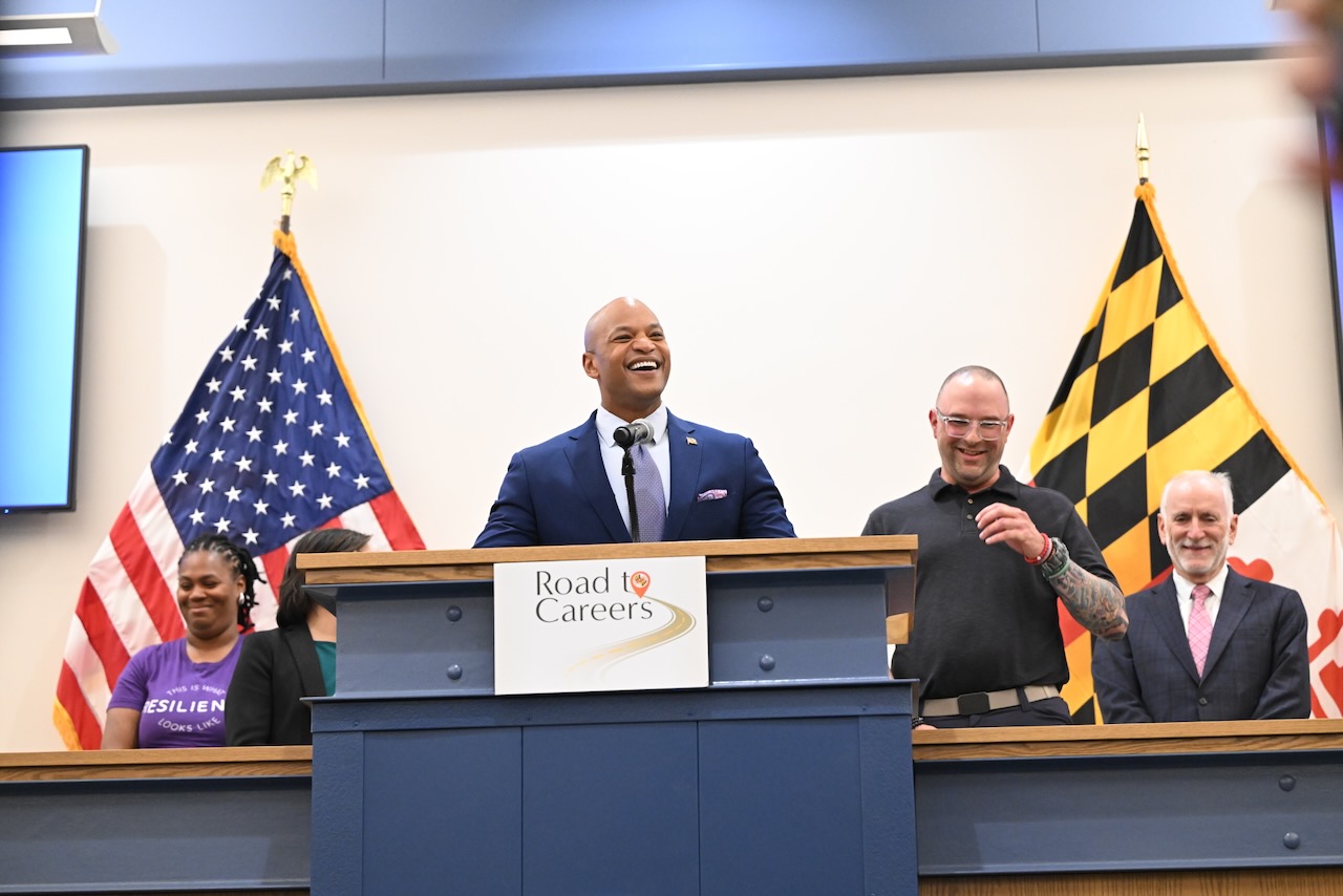 Governor Wes Moore speaks from the podium behind a sign reading "Road to Careers"