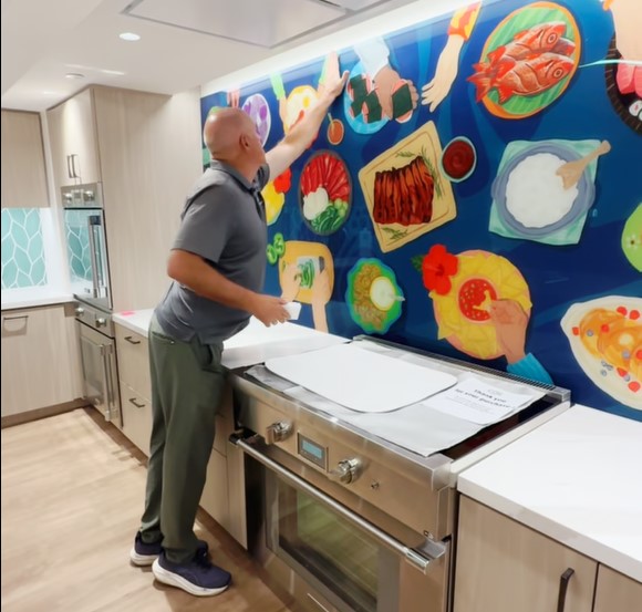 Glas_Pro's tweet photo. Joe Green does a post-installation check of a whimsical image of a dining table filled with Hawaiian food. GlasPro used special digital printing on #glass technology to create this art designed for King's Hawaiian's corporate kitchen in Gardena, Calif. #digitalprintingonglass https://t.co/uv4r5WGQ55