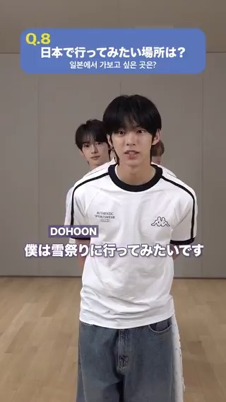 A vertical video showing a young man named 'DOHOON' speaking, with Japanese and Korean text asking 'Q.8 日本で行ってみたい場所は？' and the subtitle '僕は雷祭りに行ってみたいです'.