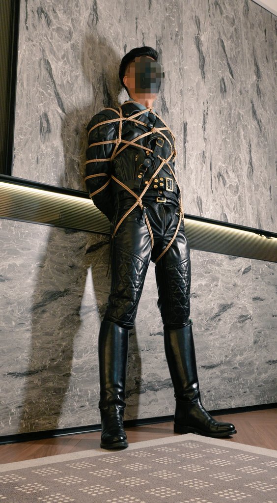 酒店房间里，身着黑色皮革马靴的人被绳索束缚于地，似陷入某种未知情境，静谧空间因这奇异画面，弥漫诡谲又神秘的气息，故事的暗流在阴影里涌动，等待被探寻 。