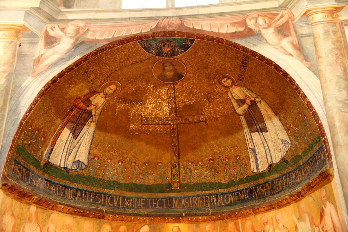 El mosaico absidal del papa Teodoro I (642-649) en la iglesia de Santo Stefano Rotondo en Roma.
Se representan una cruz gemada con el busto de Cristo sobre ella entre los santos Primo y Feliciano.