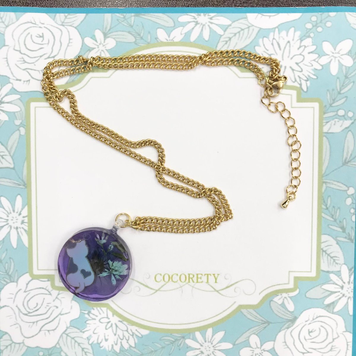 【障害者ブランド・ココリティ】山桜うさぎ作　ペンダント　「ふっくらネコとお花達」NO.3745

このペンダントは、紫のレジンにふっくらネコと花々が封入され、優しい雰囲気を演出。金色のチェーンが上品さを加え、障害者ブランド「COCORETY」の心温まるストーリーが魅力です2,000