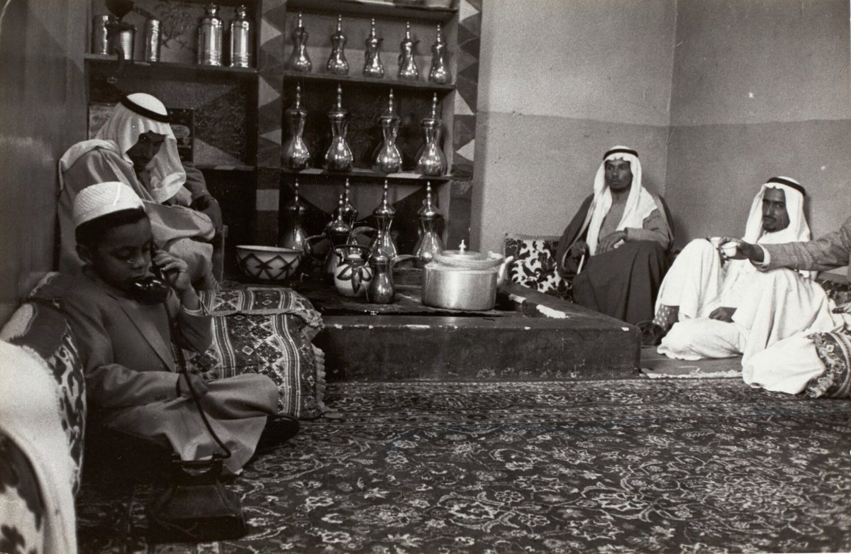 GAbalkhail's tweet image. صورة لطيفة تظهر صاحب السمو الملكي الأمير مشهور بن سعود بن عبدالعزيز جالسًا في المجلس، بين رجال يبدو أنهم من مرافقيه -رحمهم الله جميعاً وأطال بأعمار الأحياء- هنا نرى لحظة بسيطة وطبيعية: الأمير يمسك السماعة، مندمج في محادثة لا نعرف تفاصيلها، لكن مجرد رؤيته بهذه العفوية تثير…