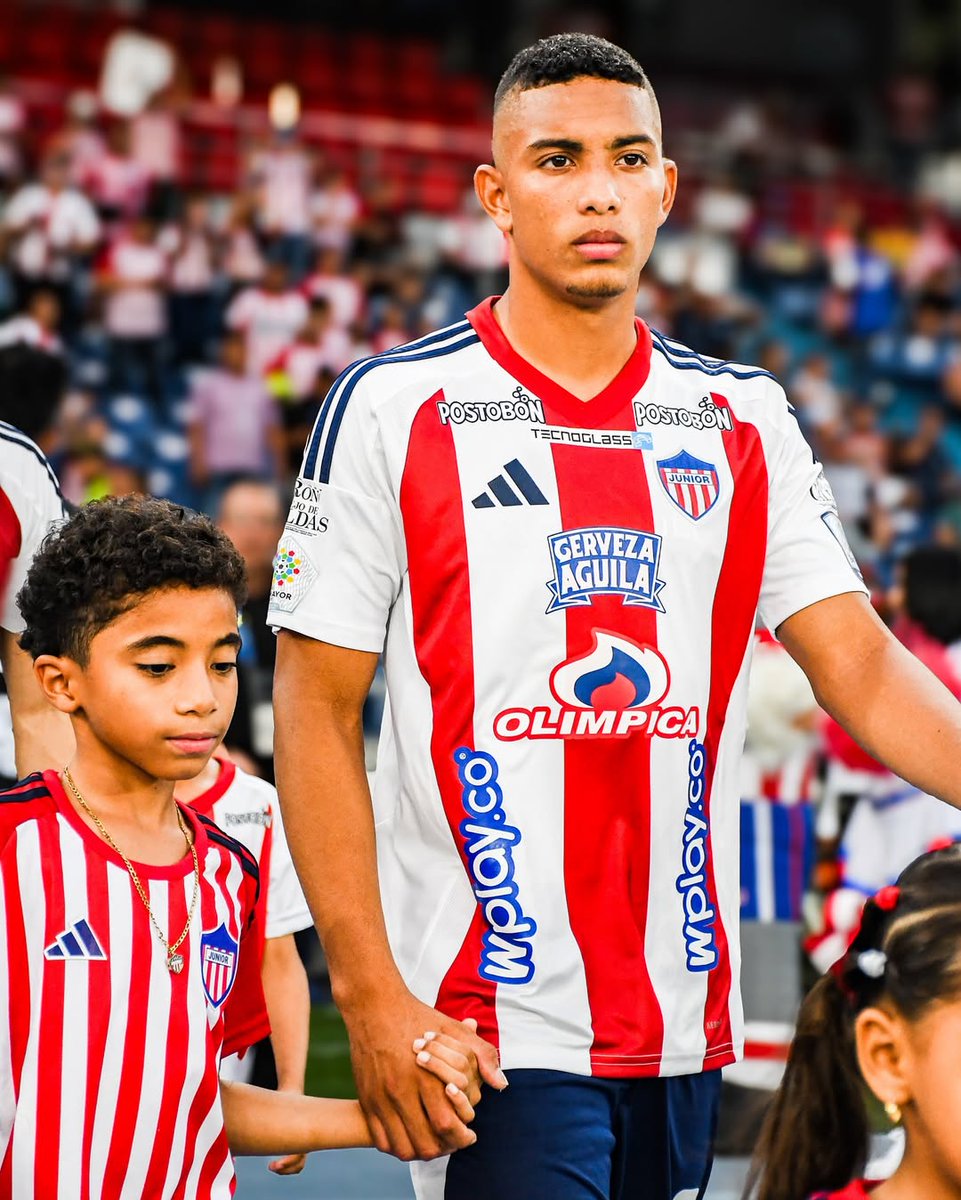 umit_ber's tweet photo. 🟡🔵🔎𝙎𝘾𝙊𝙐𝙏𝙄𝙉𝙂 𝙍𝙀𝙋𝙊𝙍𝙏 – 🇨🇴 Jordan Barrera (19) 🚨

🪄🎩Fenerbahçe’nin ve Avrupa kulüplerinin ilgilendiği Kolombiya ekiplerinden Junior takımında forma giyen 19 yaşındaki genç yetenek Jordan Barrera hakkında kısa bir derleme yapalım.

📊 Genel Profil
179 boyundaki oyuncu topa hükmetmek için yaratılmış gibi futbol oynuyor. Teknik kabiliyeti onu genç yaşlardan itibaren kendini Avrupa pazarında izlemeye gelen scoutları etkilemeye yemin etmiş derecesinde.

Dar alanda çok etkili, bileklerine hakim ve özgüvenli çalımlarla rakiplerini ekarte edebilen oyuncu, üst düzey tekniğiyle öne çıkıyor. Maç içerisinde rakibini küçük düşürücü çalımları sık sık deneyen Barrera, rabona vuruş stiliylede takım arkadaşlarına ortalar açmayı çok seviyor

Açık alanda tekniğinin yanında hızlanması da gayet iyi olan oyuncu, güçlü sağ ayağının dışında sol ayağını da etkili kullanabilmesiyle çok kolay adam eksiltme becerilerine sahip. 10 numara mevkiinde forma giyen oyuncu genellikle sol iç koridorları kullanarak içe kat edip takım arkadaşlarına ortalar açmayı tercih ediyor. Yine 10 numara mevkiisi dışında kanatlarda da oyun kurucu kanat ile yaratıcı kanat oyuncu özeliklerini birleştirip açık alan becerilerini ortaya koyabiliyor.

Bu noktada özellikle 10 numara mevkiisinde oynarken yaptığı akıllıca çevre kontrolleri sebebiyle rakipleri tek hamlede ekarte edebileceği ve takım arkadaşlarıyla verkaçlar yada kısa üçgenler kurabileceği pozisyonları alabilmesi 3. Bölgede takımına efektiflik katabiliyor.

Ayrıca oyuncu üst düzey teknik yeterliliklerinin yanında oyunu tek yönlü oynayayım da demiyor. 2. Bölge ve 1. Bölgeye gelerek takımına topu kazandırmak için birebir mücadelede bulunabiliyor. Hatta bu noktada oyuncu 8,5’dan bozma 10 numara diye adlandırabilirim.

Oyuncu salt bir 10 numara yerine derine gelerek bağlantılar oluşturan, pas opsiyonlarına dahil olan ve 2. Bölgede takım arkadaşlarıyla üçgenler yapabilen bir isim ve gerektiğinde hızlı uzun paslarıyla da kendisini dahil etmese bile takımını hücuma çıkartabiliyor. Bu noktada da paslarında ve pas oyununda çok fazla soru işareti barındıran bir oyuncu değil.
Yine duran toplarda takım arkadaşlarına ortaları ile destekleyebilen biri.

Bu yetenek setine sahip futbolculardan çok fazla fiziksel yetkinlik beklemek doğru olmaz ancak bu noktada oyuncunun 179’lik boyuyla birlikte çevik diyebiliriz. Ancak güçlü oyuncular karşısında temaslı oyunda zorlandığını biliyoruz.

Yine oyuncu genç yaştan itibaren gelecek beklentisi olan ve yeteneğine güvenenleri boşa çıkarmamış bir oyuncu olmasına rağmen saha içinde özgüvenini yüksek tutarak özellikle ceza sahasında bencillik gösterebiliyor.

Ve bu noktada da bitiriciliğinin ceza sahası dışı şutları veya ceza sahasında çok fazla iyi olmadığını da belirtebiliriz.

Barrera, 20 Yaş Altı Güney Amerika Şampiyonasında göstermiş olduğu 9 maç 1 gol 4 asist ile dikkat çekmişti. Yine geçen sezon kiralık olarak geçirdiği Kolombiya 2. Liginde 29 maç oynaması ki sadece 17 yaşındayken oynama alışkanlığı kazanması çok önemliydi.

Bu sene ise altyapısından yetiştiği kulübünde ilk 11’e girmeyi başarmış hatta bir maça kaptanlık pazubandı ile çıkarak ödüllendirilmiş biri. Totalde bu sene 14 maçta 52 dakika ortalamada 1 gol 2 asist katkısı vermiş

Saha dışında takım arkadaşlarıyla uyumlu, mütevazi bir mahallenin sokaklarından gelmesiyle gurur duyan, ailesine bağlı bir oyuncu.

Oyuncu alt yaş gruplarının hep en iyisi olarak kariyerinde henüz 18 yaşında ilk kez Kolombiya 1. Liginde ilk 11 oynadığı sezonu geçirdi. Ancak özellikle alt yaş milli takım turnuvaları olan U17 ve U20’de çok fazla izlenen ve takip edilen bir oyuncu olduğunu belirtmemiz gerek.

Bu anlamda Brezilya ekiplerinden Flemengo, Avrupa pazarından ise Porto, Napoli, Sevilla, Wolves, Borussia Dortmund ve Newcastle United gibi takımları da Fenerbahçe’nin potansiyel rakipleri. Bu da oyuncunun değerini artıran diğer unsur.

2003 sonrası doğmuş yabancı oyuncu kontenjanına böyle bir potansiyelli oyuncuların isminin geçmesinin bile çok önemli olduğunu düşünüyorum. Avrupalı scoutların elinden böyle bir yeteneği alıp, potansiyeline yatırım yapılabilecek 5-6 milyon€ ile oyuncunun gelecekte getireceği bonservisin yanında özellikle taraftarın damağında bırakacağı sihirbazlık gösterilere izlemeye değer olacaktır.

#JordanBarrera #Barrera #Fenerbahçe #Transfer #TrScouts @SportsBaseTR