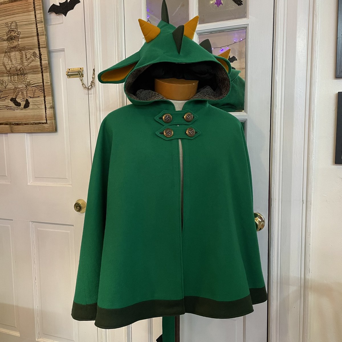 sophieraccoon's tweet image. Another custom dragon cape complete!

Made of a wool melton lined with a polyester scale textured jacquard. The cape features scales, ears, horns, and a removable tail. 
I used some vintage heraldic dragon buttons and toggles to close the front.
