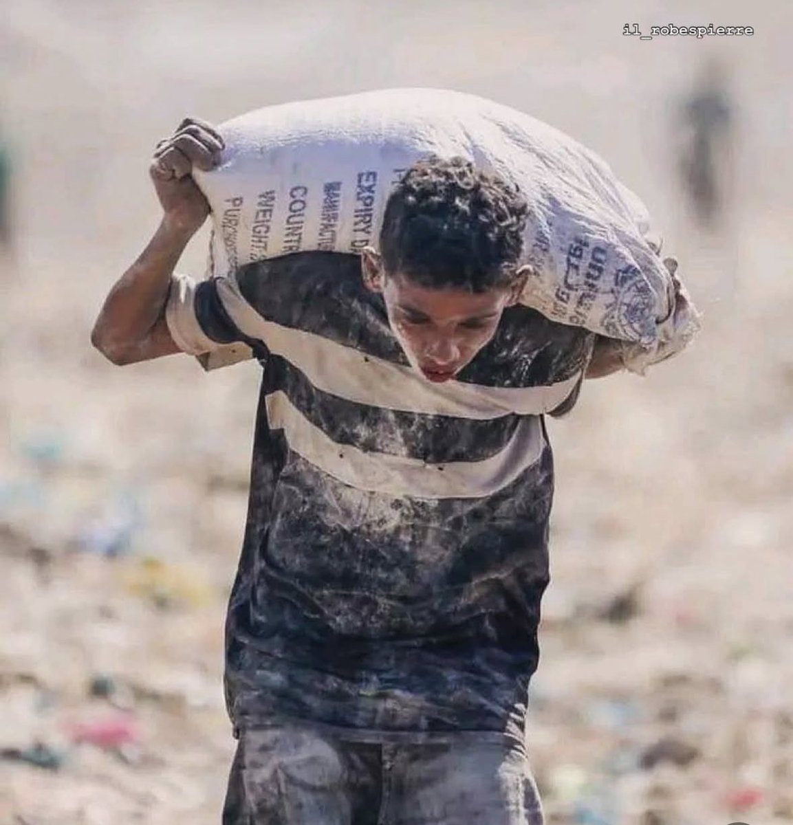 Un ragazzo. Non ha l’età per portare sulle spalle il mondo, eppure lo fa: piegato sotto un sacco di farina più grande di lui, coperto di polvere e disperazione. Non gioca. Non sogna. Lotta. Per vivere. Per far vivere. Perché a Gaza oggi si muore anche solo per un pugno di pane.