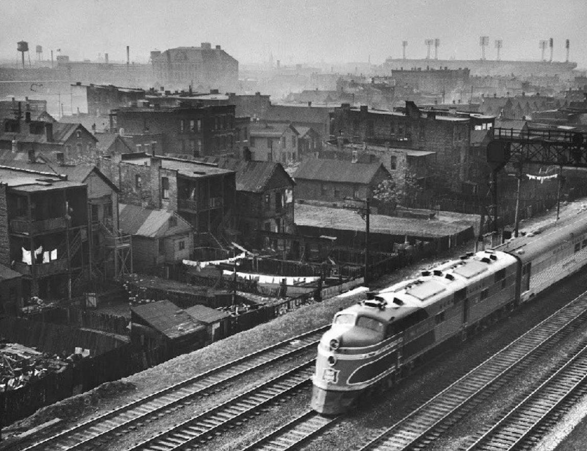 Chicago, Ill, ca 1945 - You might take a quick glance at this photo of a Rock Island diesel train chugging through an old Windy City neighborhood and wonder what does it have to do with baseball, but then you'll look in the distance and see Comiskey Park looming large