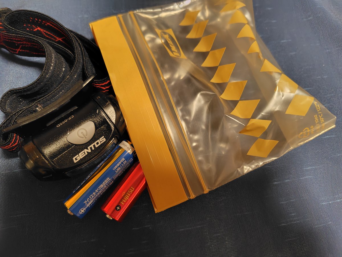 よいこのみんな、ヘッドライトは登山に必携と言われているけれど、ふだん日中の日帰りしかしなくて、まずヘッドライトなんか使わないよ、という人は、この写真のように「普段使っている電池１組はヘッドライトから抜いた状態で」「それと別に予備の電池が１組」を、ジップロックに入れた状態で持ち歩く