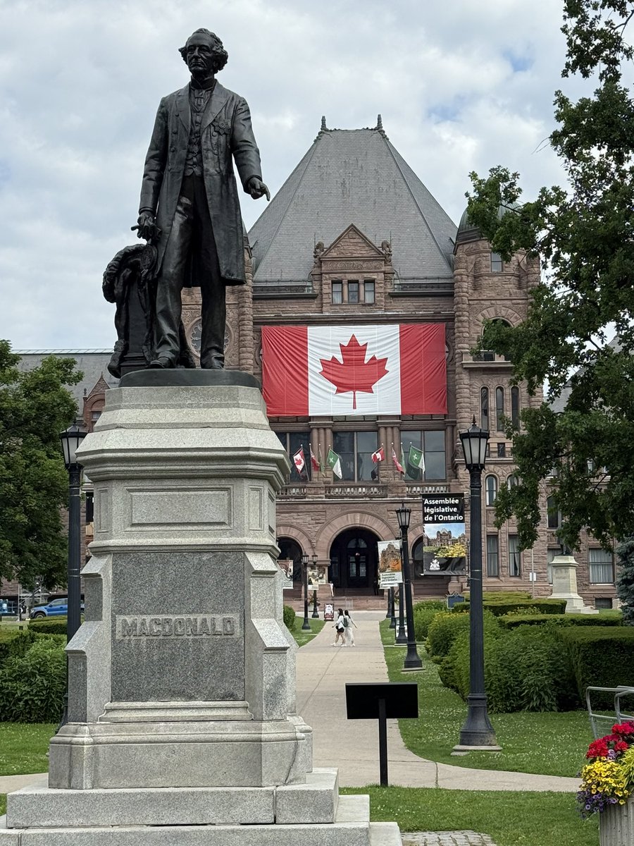 Happy to report that I walked past Sir John A’s statue while walking Chloe the Wonder Dog this morning. No graffiti. 
And check out that huge and amazing Canadian flag on the legislature at Queen’s Park in preparation for their big Canada Day party next week.