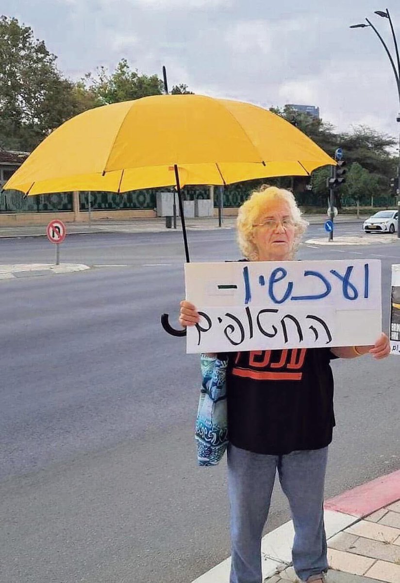 יום שני בבוקר / צומת המשכן לאמנויות הבמה / באר־שבע

אישה בת 73 עומדת בצומת החם וכל כולה זעקה דוממת. השמשייה הצהובה, החולצה וגם השלט מבקשים דבר אחד: לא לשכוח ולא להשכיח את החטופים שעודם בעזה. 

הימים ימים רעים. אזעקות וריצה בהולה למקלטים בזמן שטילים בליסטיים נורים ללא הרף. אבל