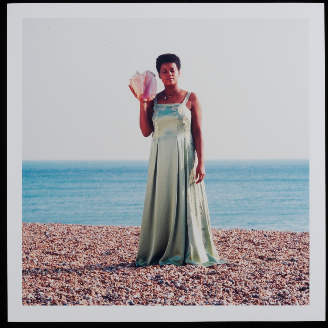 V_and_A's tweet image. Ingrid Pollard, pioneering Black British photographer and ABP founder, challenges cultural stereotypes in her Self-Evident series. Portraits of black men and women in the English countryside, each holding objects linked to the Afro-Caribbean diaspora.