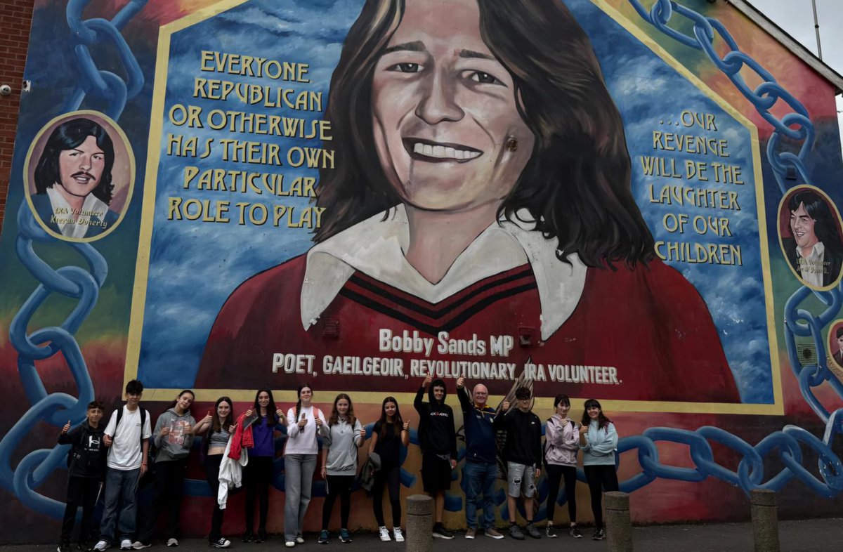 Ffeirste's tweet image. Jake MacSiacais i mbun turais Slí na Gaeltachta le páistí ó Thír na mBascach. Ag muirmháisiú agus uaigh Bobby Sands. Tá na páistí ar campa samhraidh coicíse i mBéal Feirste.
A group of Basque Students on Slí na Gaeltachta Tour today, visiting the Bobby Sands Mural. #Gaeilge