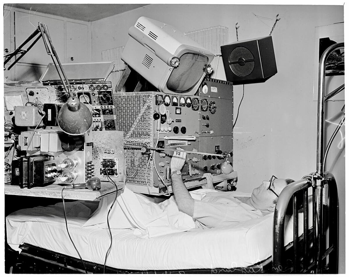Seems a bit extreme however Ben Ragland a disabled radio 'ham' operator here in his bed surrounded by radio transmitters, receivers, etc.1960.
The weight of that table, and a soldering gun!?