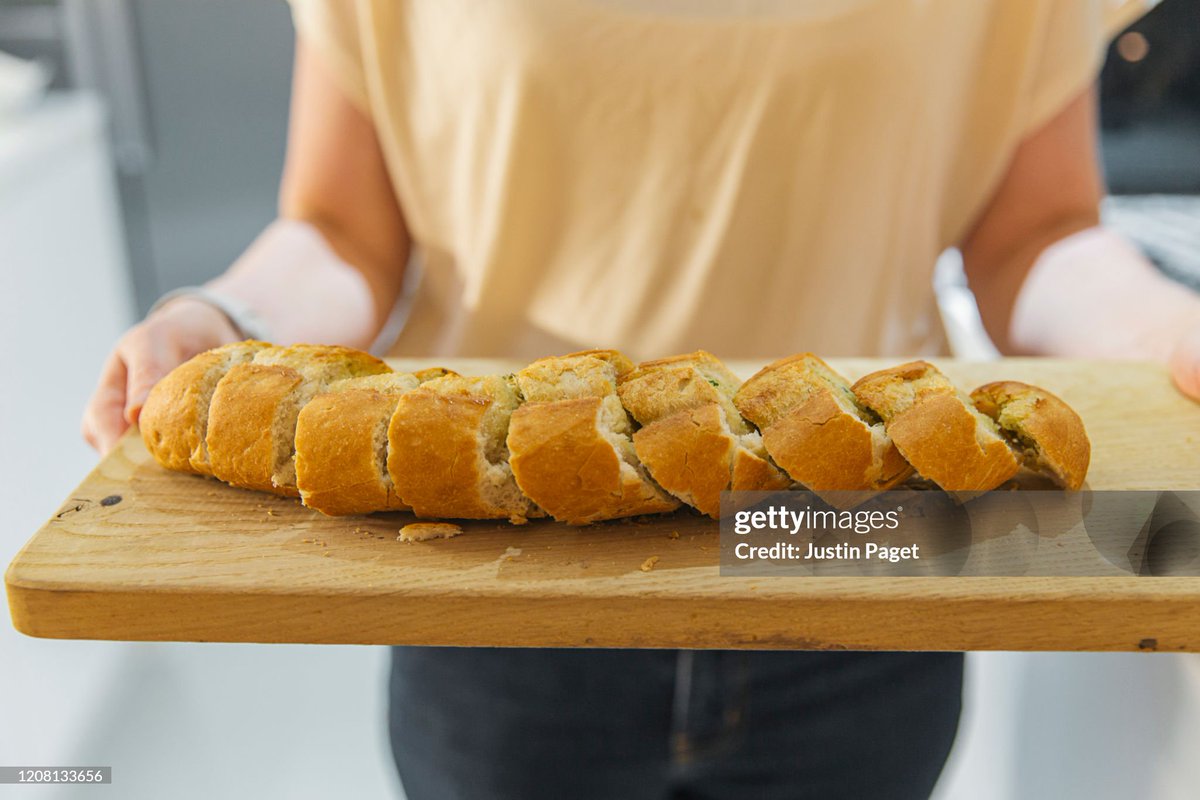 shitbritishpics's tweet image. Woman holding wooden board with garlic bread - stock photo (2020)