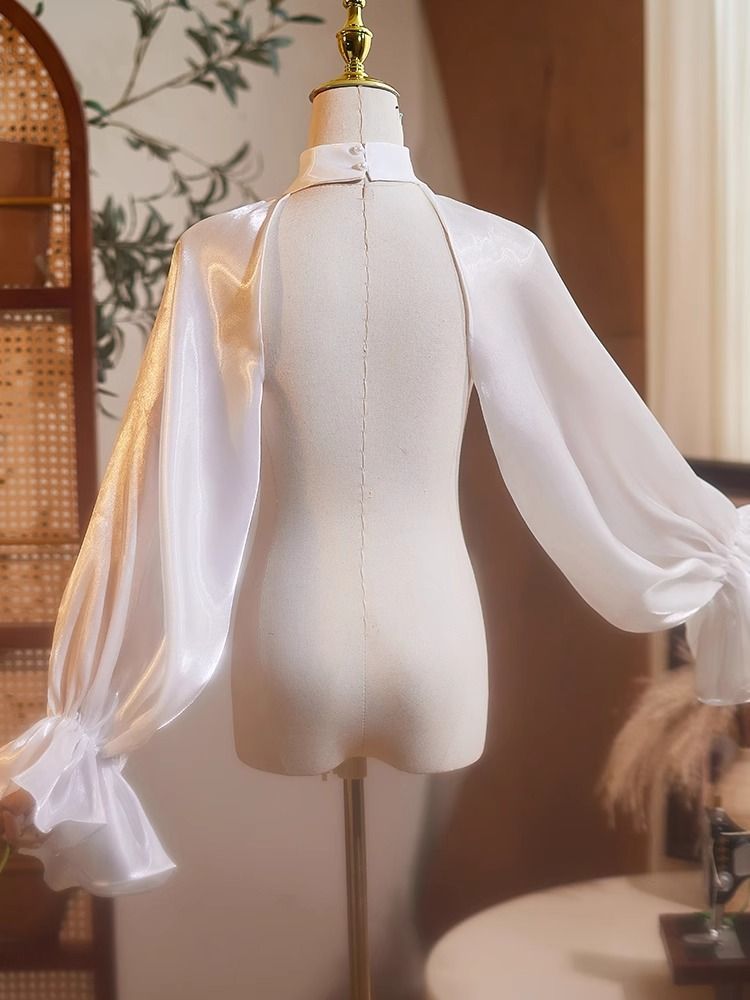 王侯貴族のボレロトップス - White 
manus-machina.com/collections/ne… 
ヴィクトリアン調の優雅さを放つボレロトップス。ハイネックのデザインが上品さを引き立て、肩から袖にかけて流れるように広がるシアーオーガンジー素材のパフスリーブが、空気を含んだような立体感を演出しています。