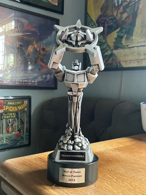 SimonFurman3's tweet image. Getting ready to record ep. 26 of The Rest is Giant Robots (w. Andrew Wildman) and while discussing the origins of Regeneration One (ep. 24) I promised I'd unearth my #Transformers Hall of Fame 'gong' (given me in 2012) and wave it at the camera! Et voila! patreon.com/Wildfurproduct…