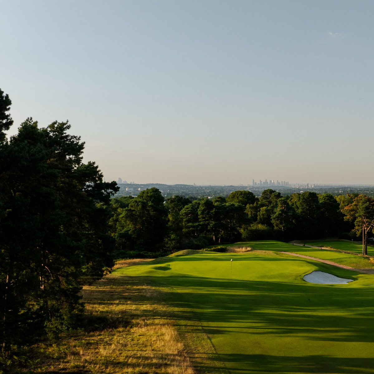 TheAddingtonGC's tweet image. The 14th green with London’s skyline in the distance.
The fairway here will soon hug the tree line, which covers a cliff-like drop, allowing players to chase the preferred angle up the left and flirt with a hazard that has been hidden for generations.