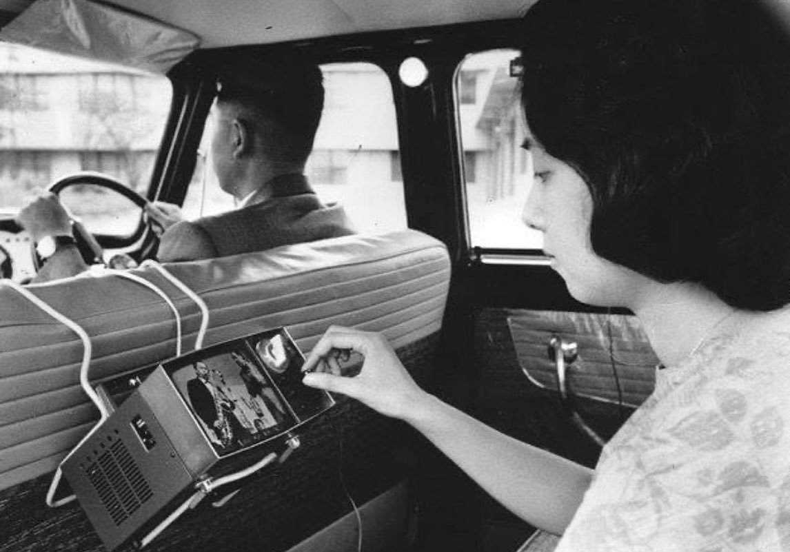 ComputerLove_'s tweet image. A woman in Japan using one of the first portable TVs in a car, developed by Sony. (1963)