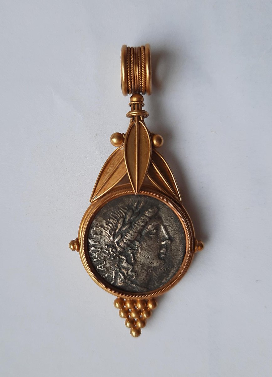 ClassicalMyths's tweet image. Gold pendant set with a silver Roman denarius featuring Salus, the goddess of health & safety. The setting dates to ca. 1870 & was created with laurel leaves and berries in the "archaeological revival" style popular at the time. Photo: British Museum.