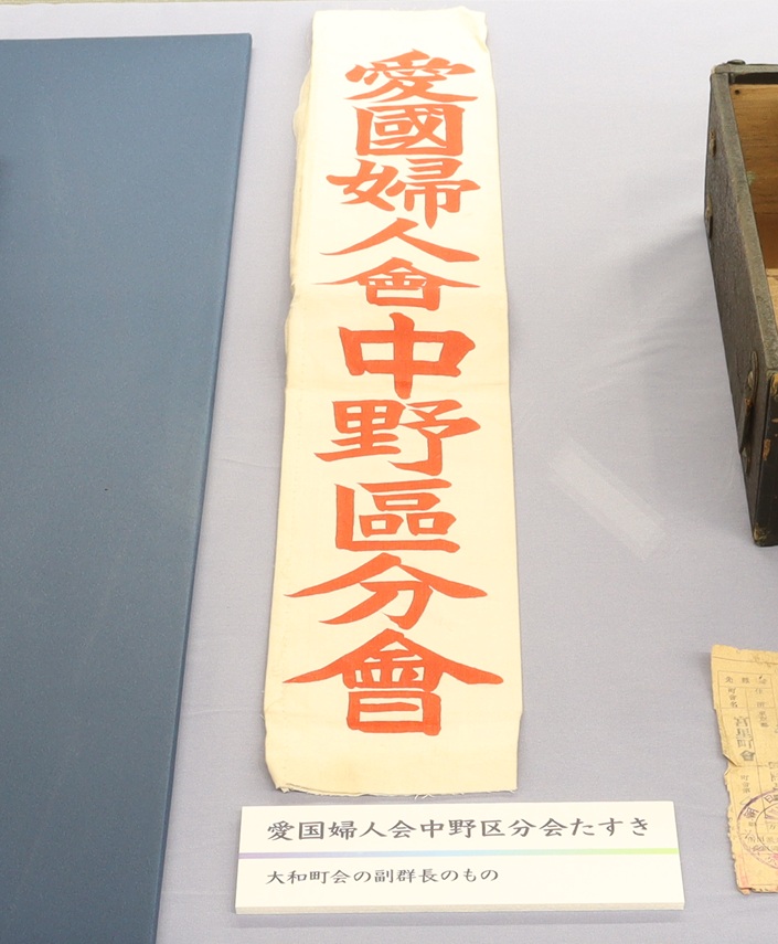 nakano_rekimin's tweet image. 〈企画展「中野区の戦後80年」開催中〉
愛国婦人会中野区分会のたすき。
男子壮青年が徴兵されていく中、「銃後の守りは女性で」のスローガンのもとに、防空演習、建物疎開まで女性たちが行いました。
銃後とは直接戦闘はしないが戦争に何らかの形でかかわることです。
#中野区の戦後80年
