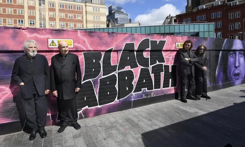 Cuando  cuatro obreros de Birmingham encendieron la distorsión, el mundo nunca  volvió a sonar igual. Hoy, frente al mural, no posan músicos: posan  leyendas que fundaron un género con riffs más pesados que la historia  misma. BLACK SABBATH no envejece, petrifica.