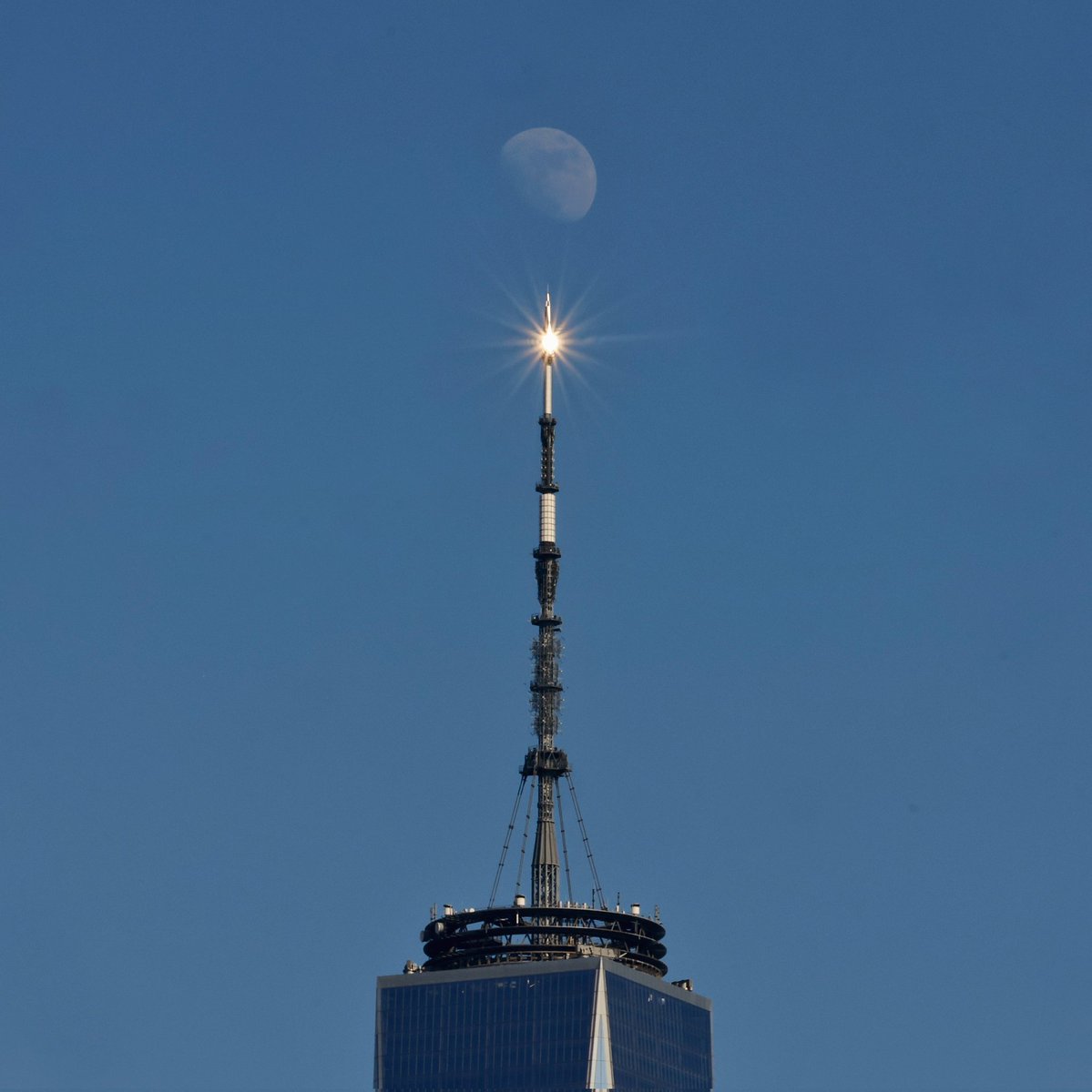 A 78 percent illuminated waxing gibbous moon rises above One World Trade Center as the sun reflects off the top of the building's antenna in New York City, Saturday evening #newyorkcity #nyc #newyork #moon @wtc