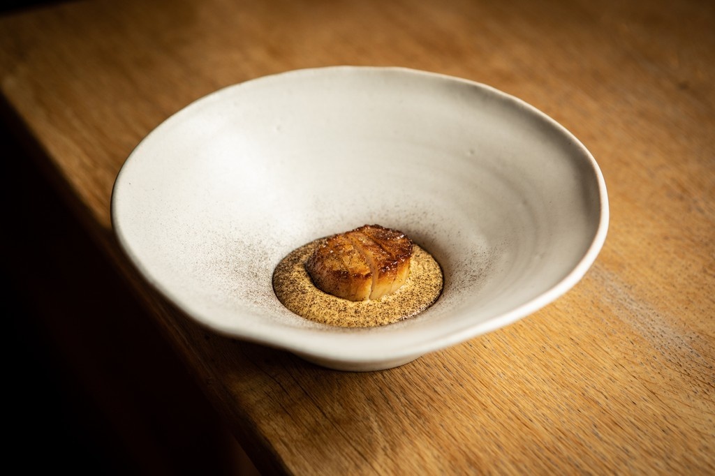 Hand-dived scallops, roasted in butter for caramelisation, glazed with spruce honey and fresh spruce tips, then dressed in brown butter and dusted with a powder made from barbecued celeriac skins.