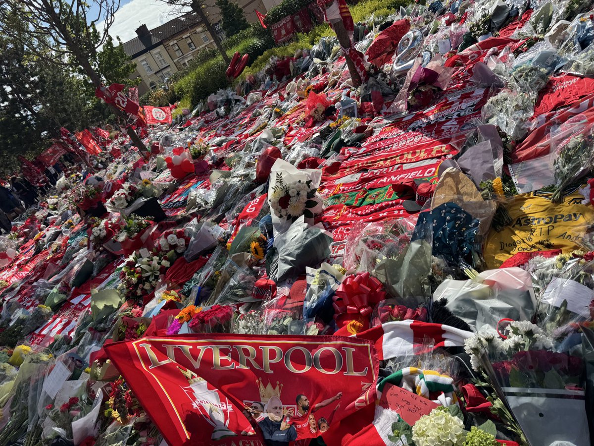 JamesPearceLFC's tweet image. Tributes to Diogo Jota and his brother Andre Silva now cover the entire length of the Main Stand and beyond, from Anfield Road to Walton Breck Road. Flowers, scarves, shirts, hats, flags, banners, even PlayStation controllers. 
An outpouring of love and grief.