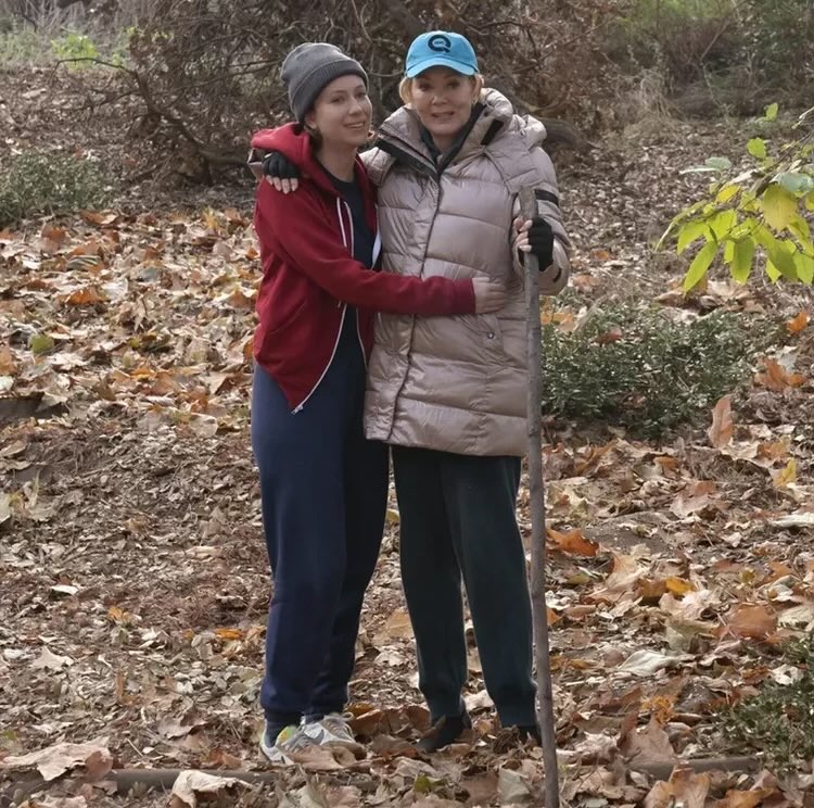 hacksmediareact's tweet image. hannah einbinder and jean smart posing in the woods / hacks backstage set s3