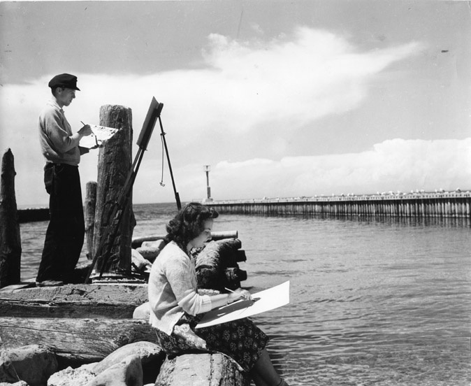 #DYK that Michigan State College students had the opportunity to participate in the Leland Summer Art School? This photograph taken in July 1940 shows two students painting on a pier in Leland, Michigan. #MSUHistory