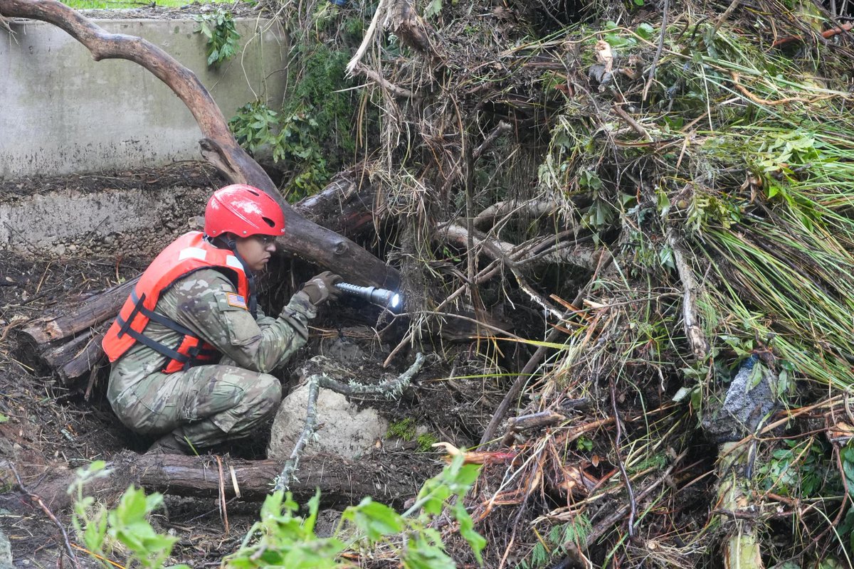 TXMilitary's tweet image. Texas National Guard service members assigned to Task Force Storm work in teams along the Guadalupe River bank conducting search and rescue operations and removing debris near Camp Mystic in Kerr County, Texas.