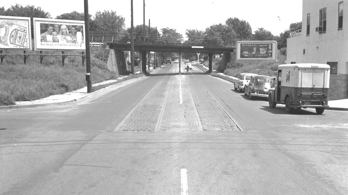 #OnThisDay July 7 1960: A view looking east on Como Avenue Southeast as the former Como-Harriet-Hopkins interurban streetcar tracks are paved over. The bridge in the background carries the Northern Pacific Railway.
