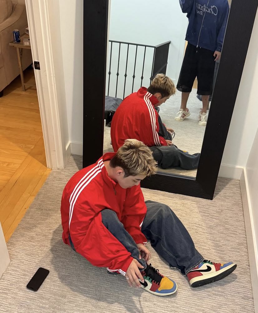 Rockin’ the classic red Adidas zip-up like I just walked out of a 90s music video, lacing up the multi-color kicks that are screaming personality without saying a word. Mirror check in the back says I’m locked in. The phone’s down, but the energy’s up.