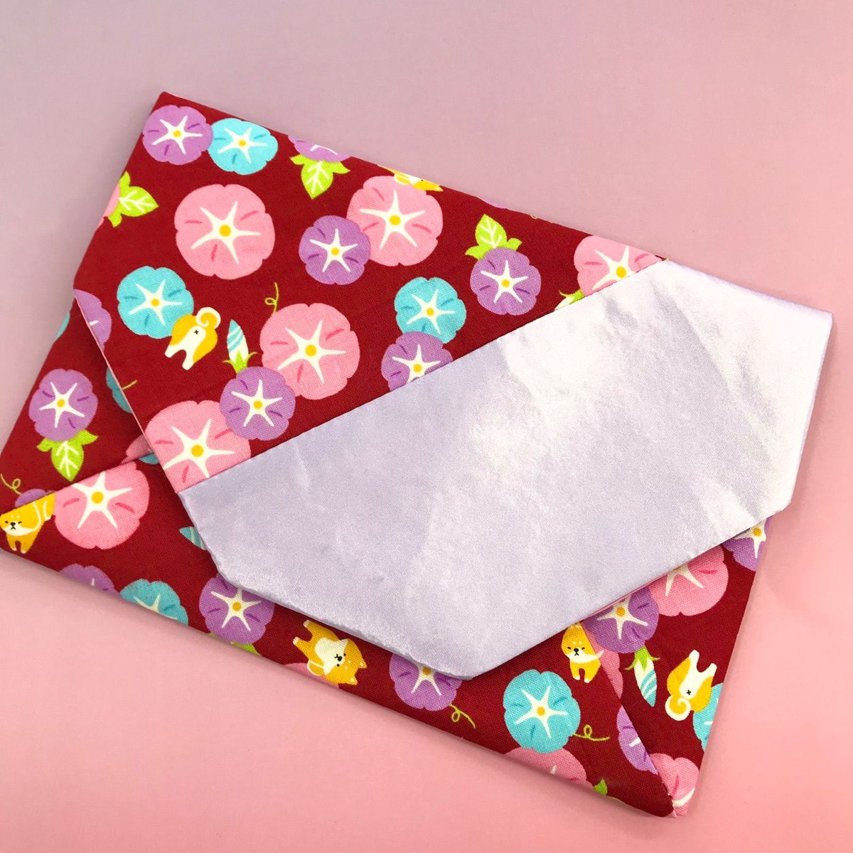 【福祉施設制作】癸（みずのと）作　御朱印帳袋　「朝顔と柴犬」　NO.3795

この御朱印帳袋は、朝顔と柴犬の可愛いデザインが魅力。赤を基調にカラフルな花と犬が描かれ、和風の美しさと遊び心を両立。光沢のある白い布が上品さを加え、持ち運びにも便利です￥1,200