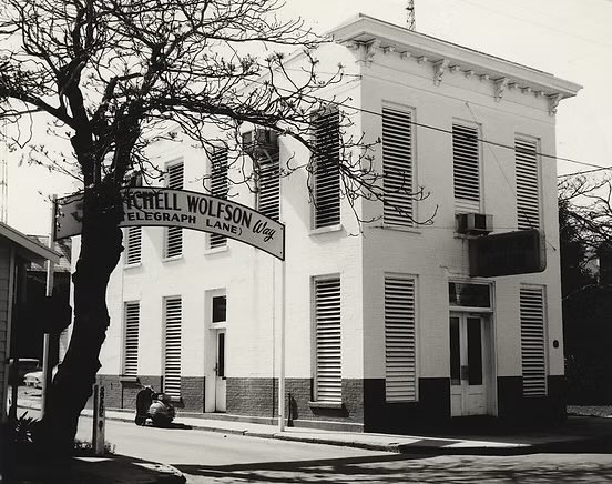 July 8, 1962 – Key West City Commissioner John dePoo was demanding that the archway signs proclaiming Telegraph Lane to be “Mitchell Wolfson Way” be removed as they had never been formally approved.