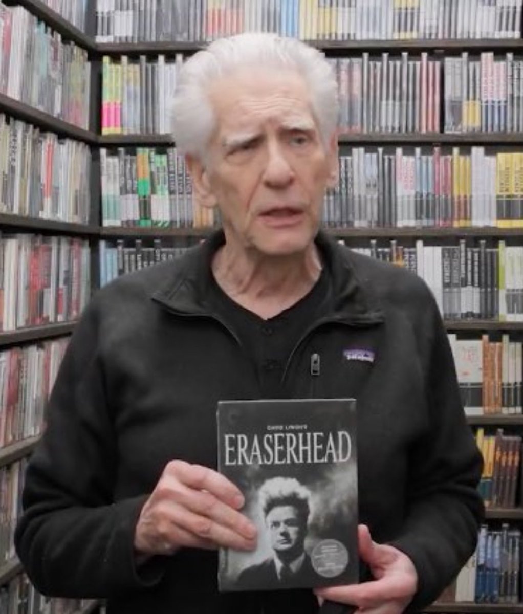 TheCinegogue's tweet image. David Cronenberg holding a copy of David Lynch’s Eraserhead in the Criterion Closet