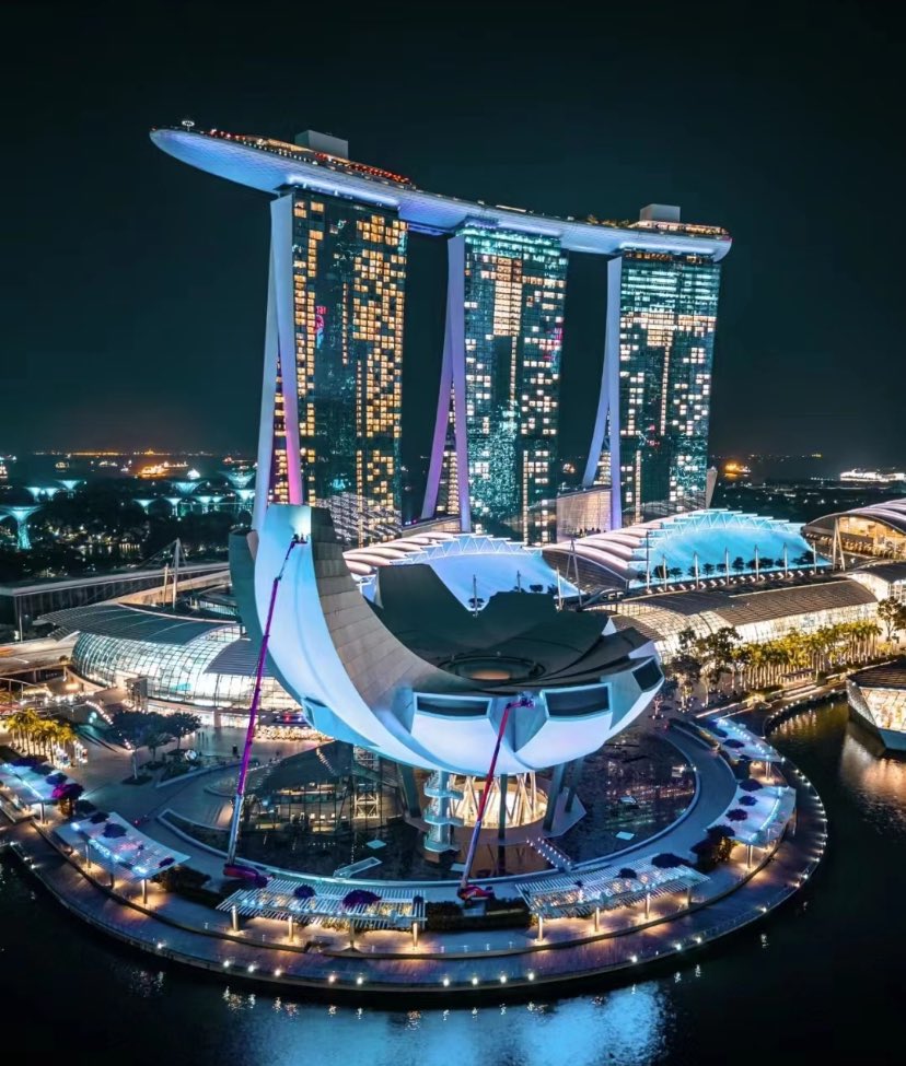 Marina Bay Sands soi bóng nước trong,Ba tòa tháp cao vươn trời rộng, Cầu nối ánh sáng, đẹp tựa giấc mơ.
Lá phượng hoa bung giữa không trung, Ánh đèn lấp lánh, sắc màu lung linh, Dòng sông phản chiếu khung cảnh huyền ảo,Singapore đêm, thơ mộng ngất ngây.
