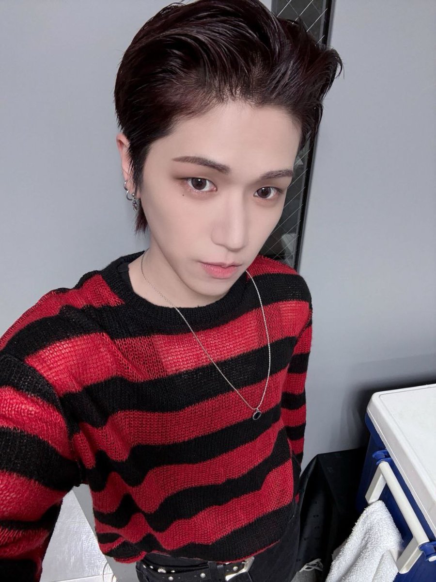The textured sweater, reminiscent of vintage punk aesthetics, is elevated with modern finesse through meticulously styled accessories silver hoop earrings, stacked rings, and a minimalistic pendant necklace that glints like punctuation on a visual statement.